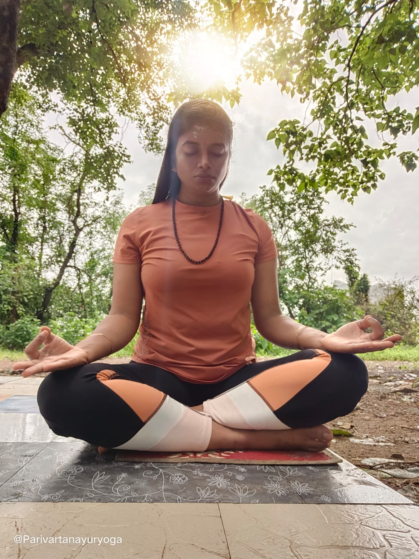 Dr. Rashmi practising meditation outdoors beneath the trees